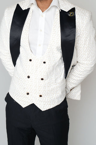 Man wearing a white textured vest over a black vest with a white shirt on a gray background